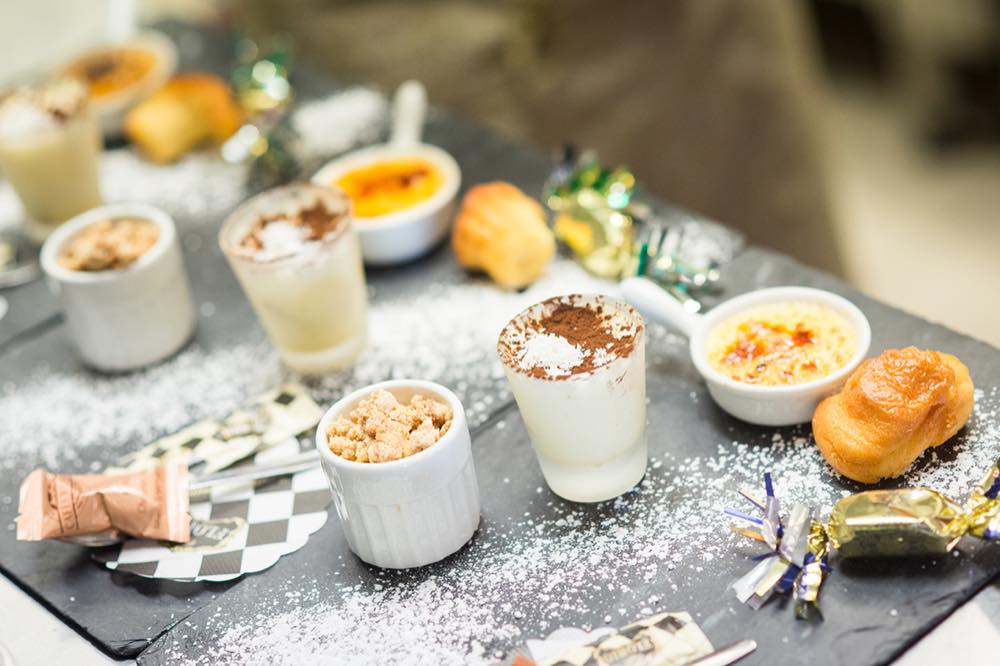 Assortiment de desserts servis sur une ardoise : tiramisu, crème brûlée, crumble, chouquette
